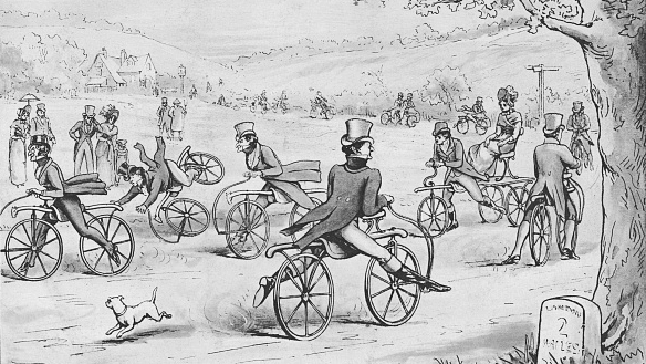 A black and white image from 1894 of men in tailcoats and top hats riding bycyle like contraptions powered only by pushing their feet off the ground along a country lane.